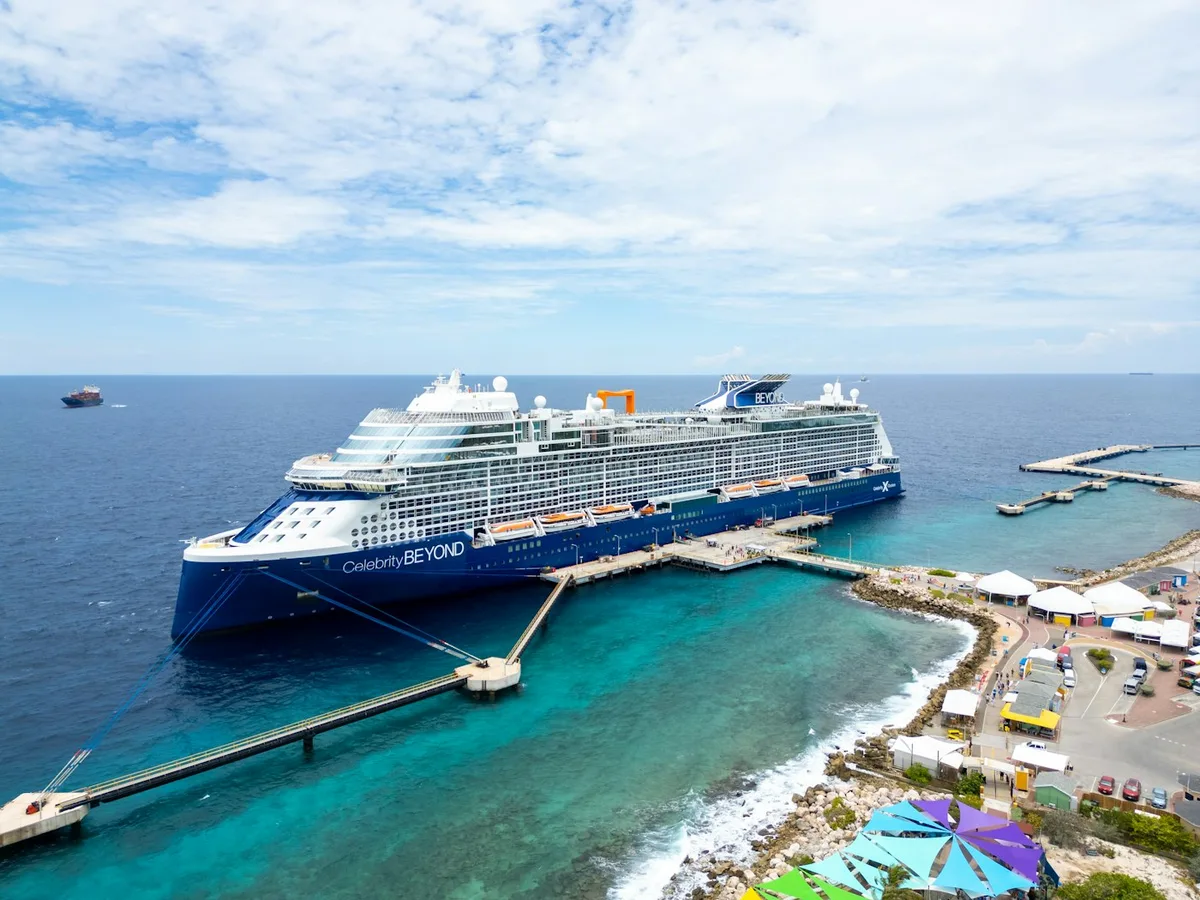 A cruise ship docked at a pier in blue water
