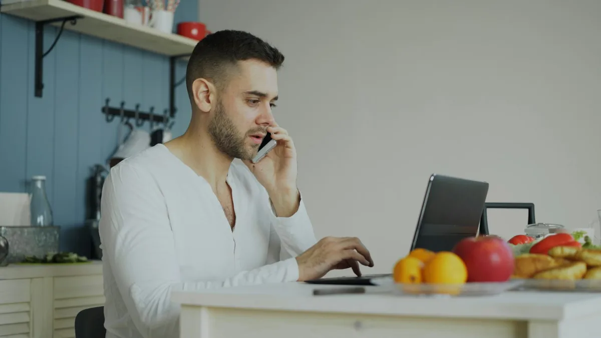 A man on the phone at his kitchen table