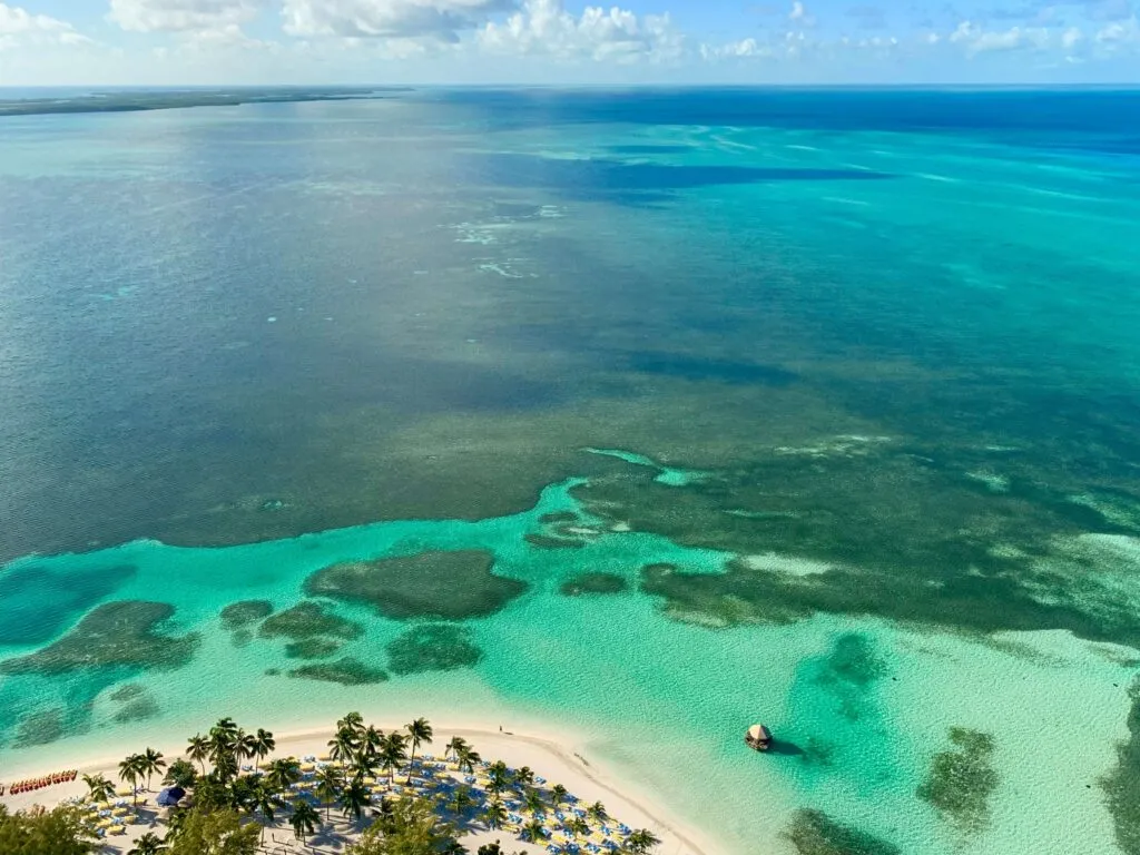 Aerial view of the Bahamas islands showcasing stunning turquoise waters surrounding lush green islands with pristine white sandy beaches and coral reefs visible beneath the clear sea.