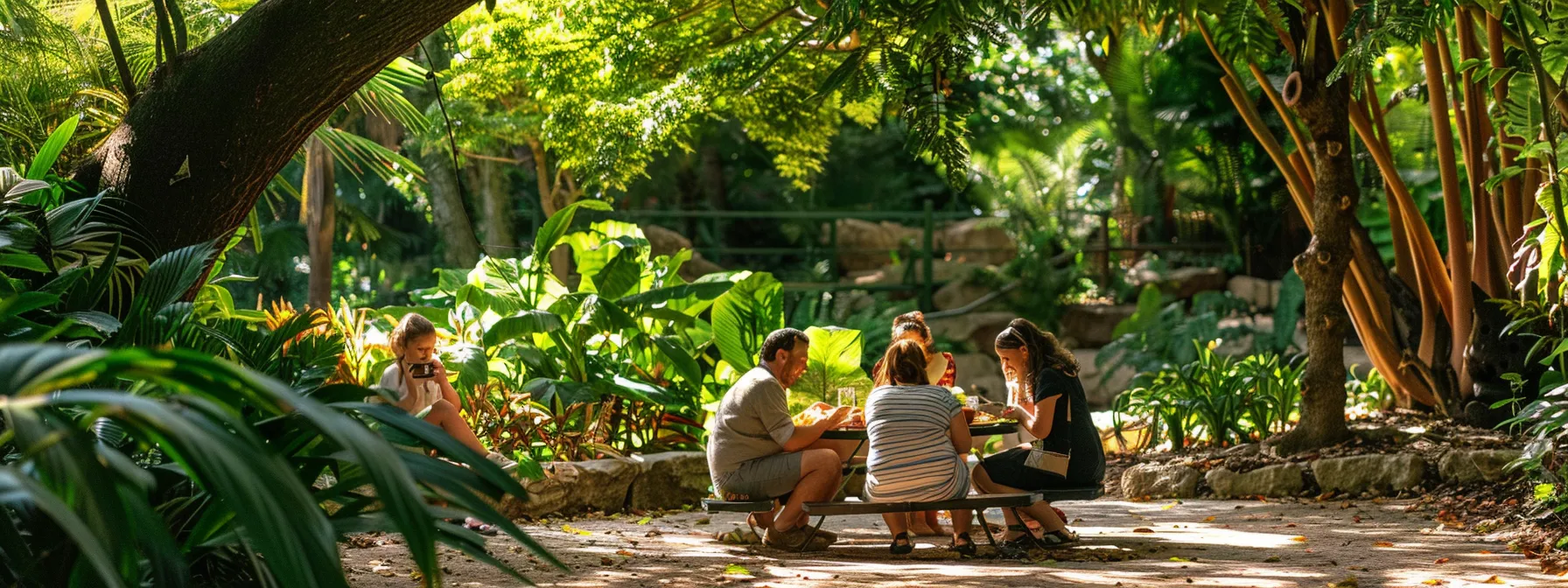 a family picnicking under the shade of a tree surrounded by lush greenery and enjoying a meal together at cleveland metroparks zoo.