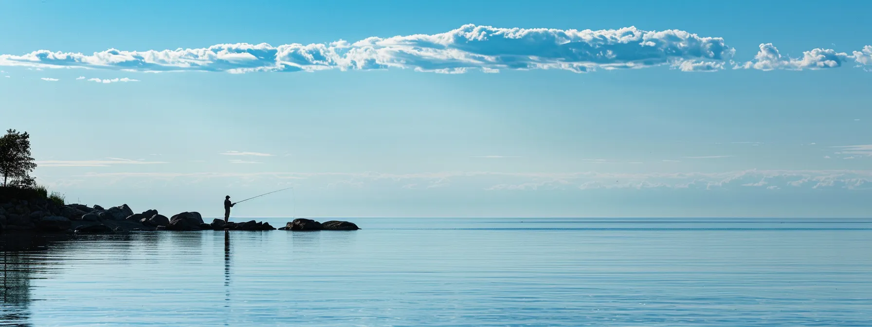 a lone angler casting a line into the calm waters of lake erie, surrounded by picturesque shoreline and abundant fishing spots.