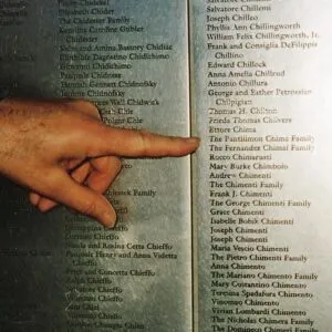A finger pointing to the Chima family name on an immigration honor wall